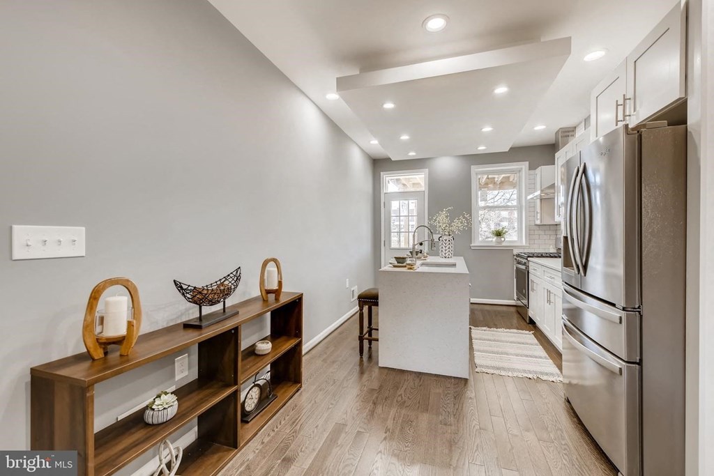 a white kitchen with a stainless steel refrigerator and a sink