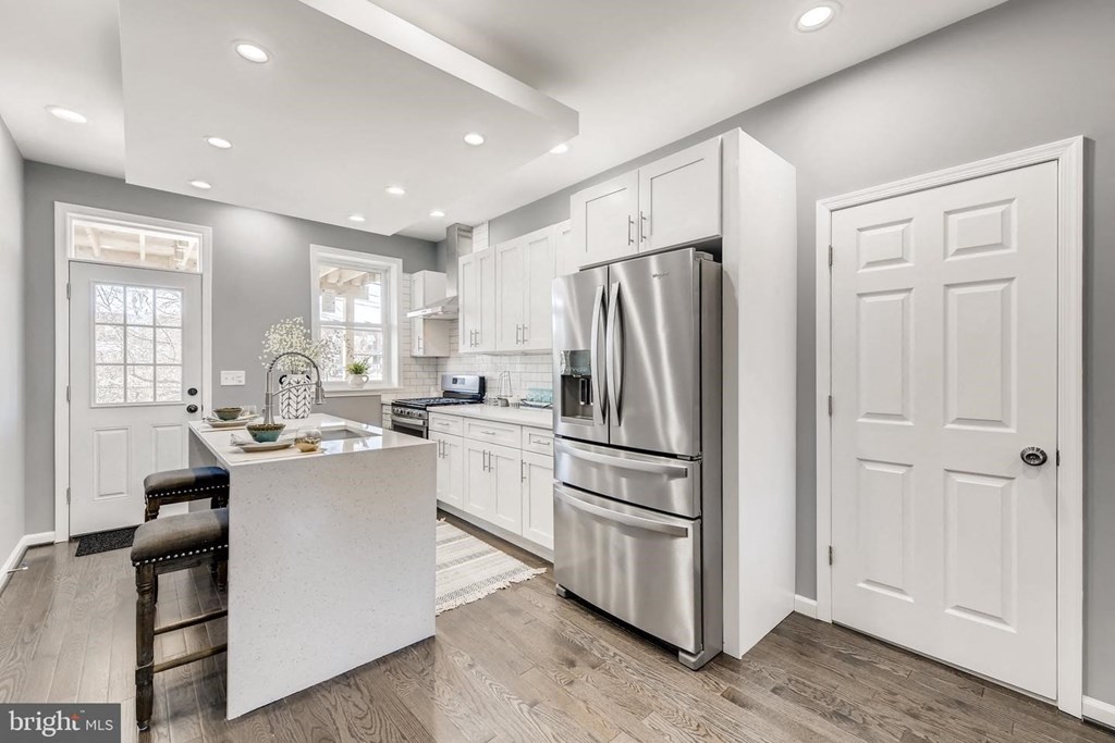 a white kitchen with a large stainless steel refrigerator