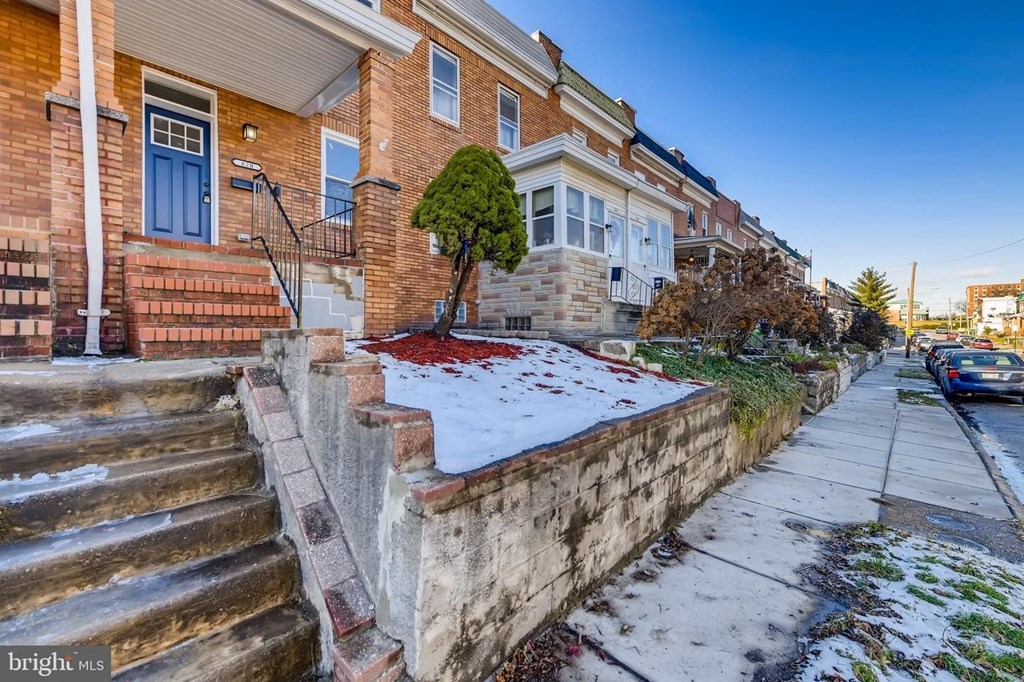 a snow covered sidewalk in front of a brick house