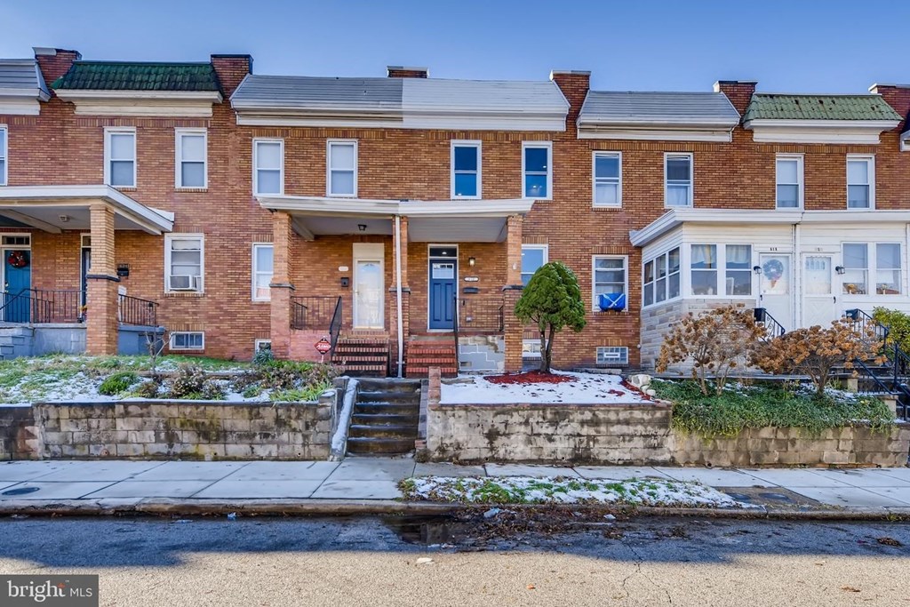 a red brick house with snow on the sidewalk
