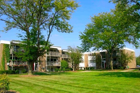 a row of apartment buildings with green grass and trees