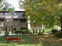 an apartment building with a red bench in a park