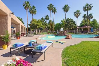 a pool with lounge chairs and a water fountain and palm trees