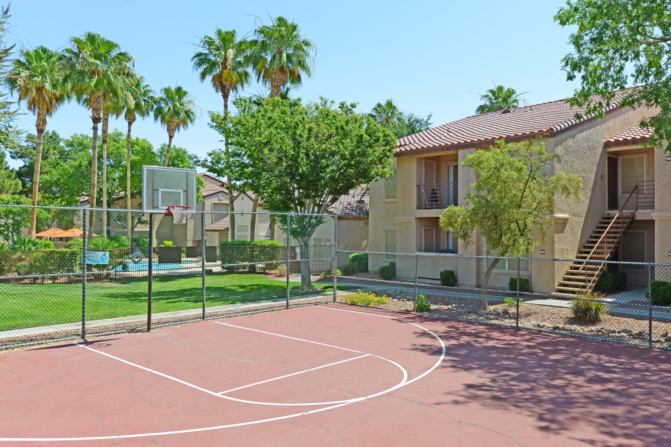 a basketball court in front of apartments with palm trees