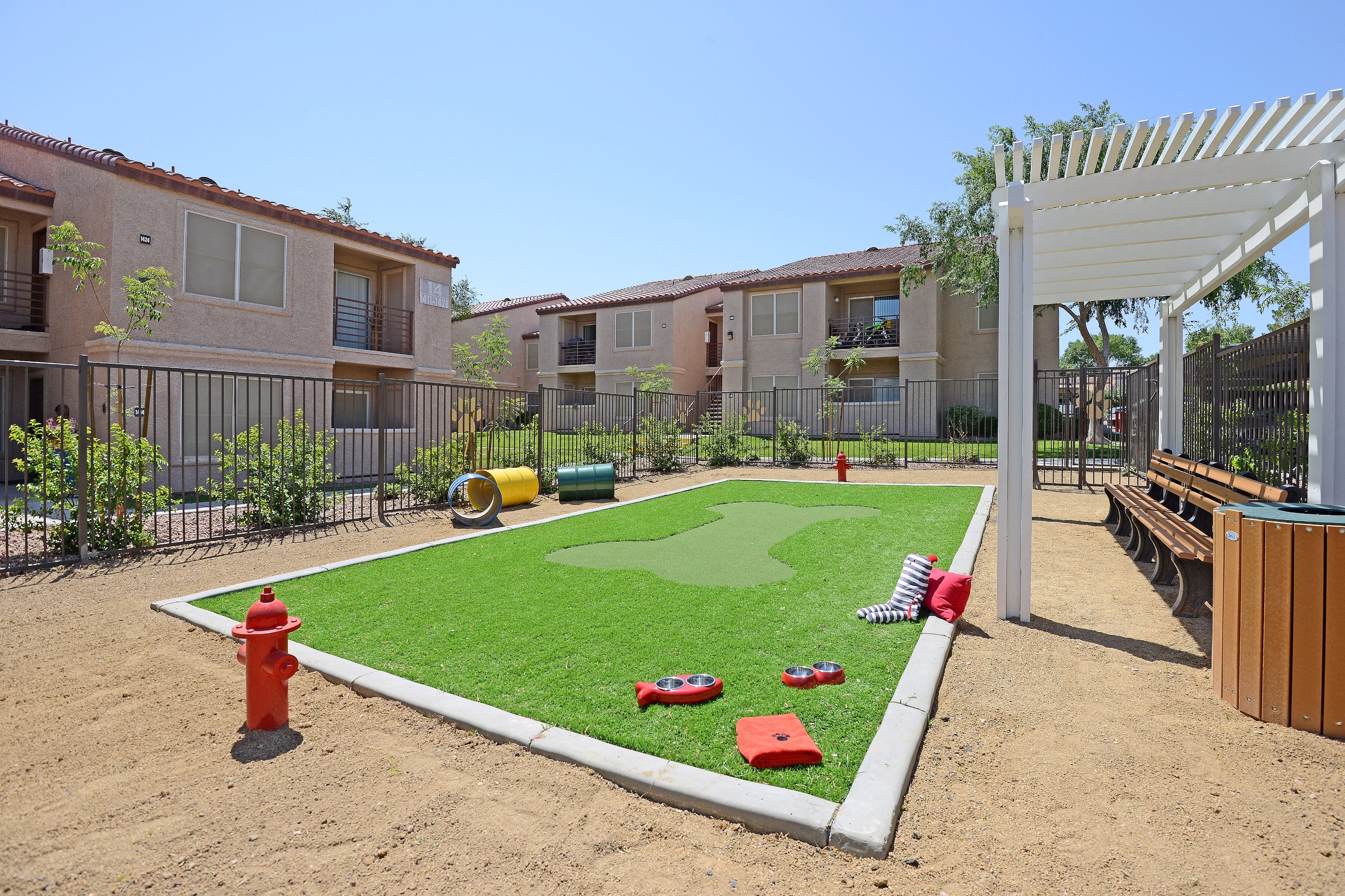 an outdoor play area with grass and a fire hydrant