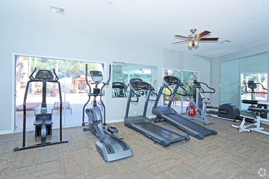 a gym with several machines and a ceiling fan