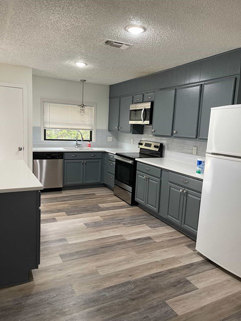 a renovated kitchen with gray cabinets and a wooden floor