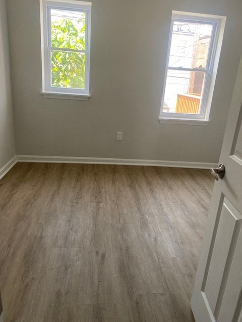 a empty room with a wooden floor and two windows