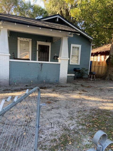 an empty yard in front of a blue house with a fence
