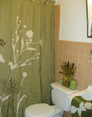 a bathroom with a green shower curtain and a toilet