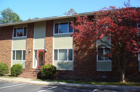 an apartment building with a red tree in front of it