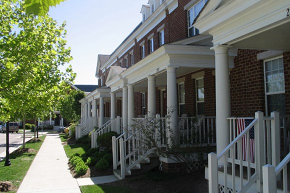 a row of houses with white porch pillars and a sidewalk