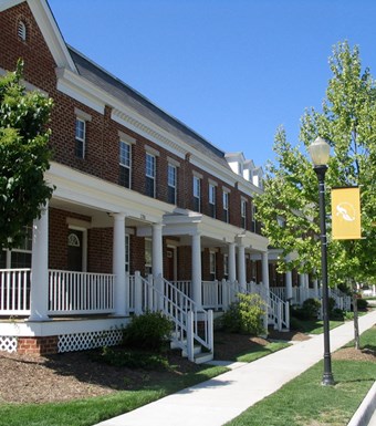 the front of a brick building with white porch railings and a street light