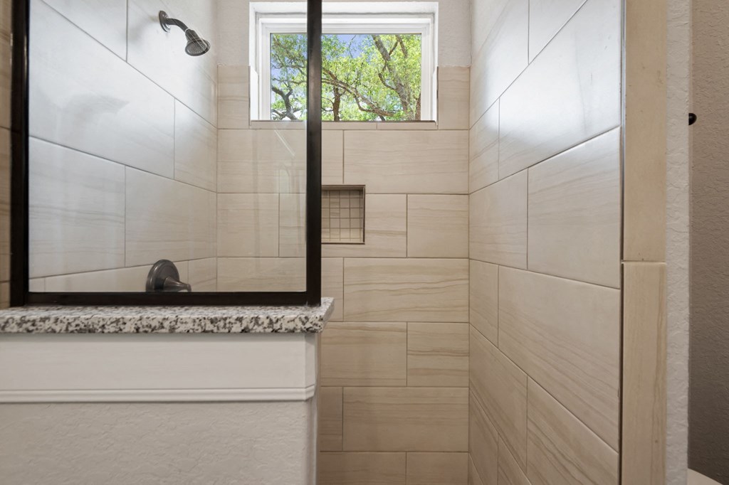 the bathroom has a large mirror and a shower with a window