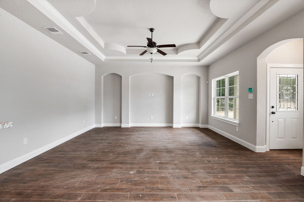 an empty living room with a ceiling fan and a door