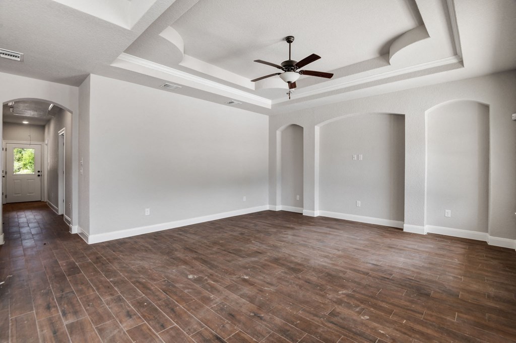 an empty living room with a ceiling fan and wood floors