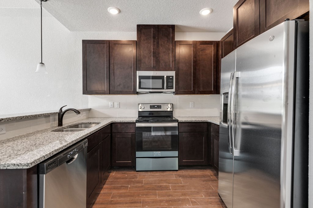 a kitchen with stainless steel appliances and a marble counter top