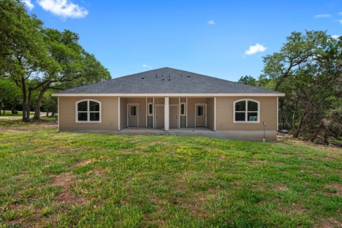 the front of a house with grass and trees