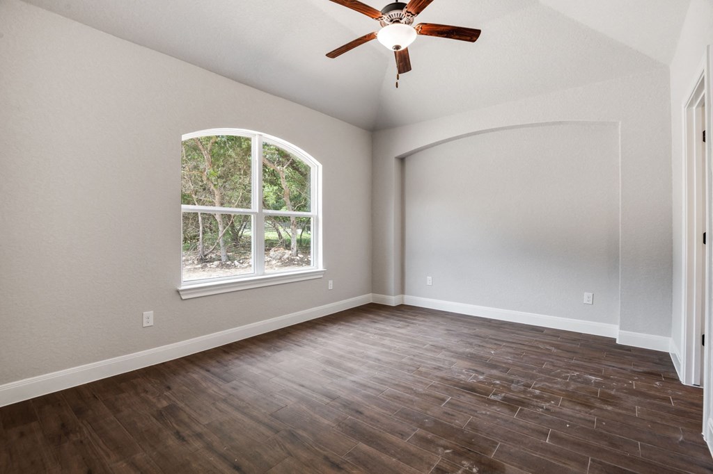 an empty living room with a window and a ceiling fan