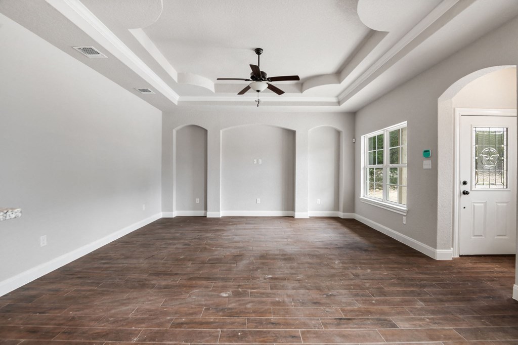 an empty living room with a ceiling fan and a door