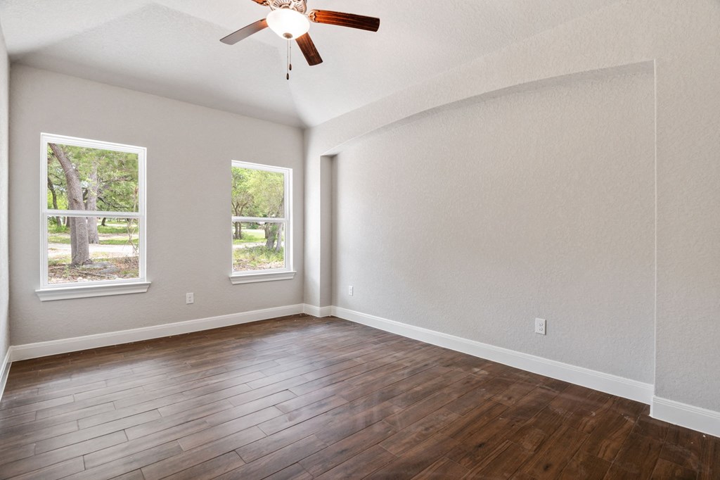 the spacious living room with hardwood floors and a ceiling fan