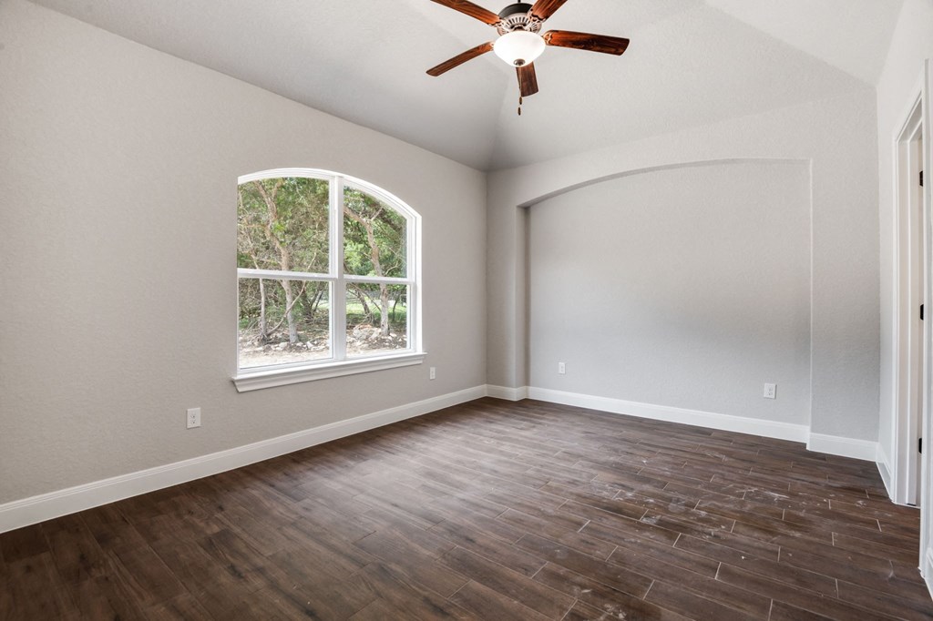 an empty living room with a window and a ceiling fan