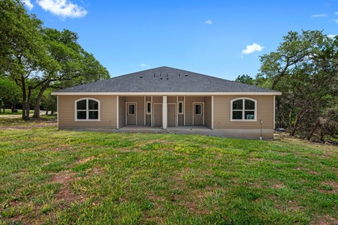 the front of a house with grass and trees