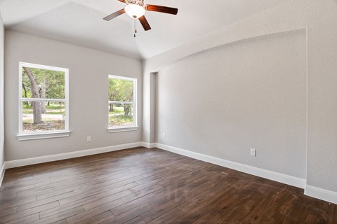 the spacious living room with hardwood floors and a ceiling fan