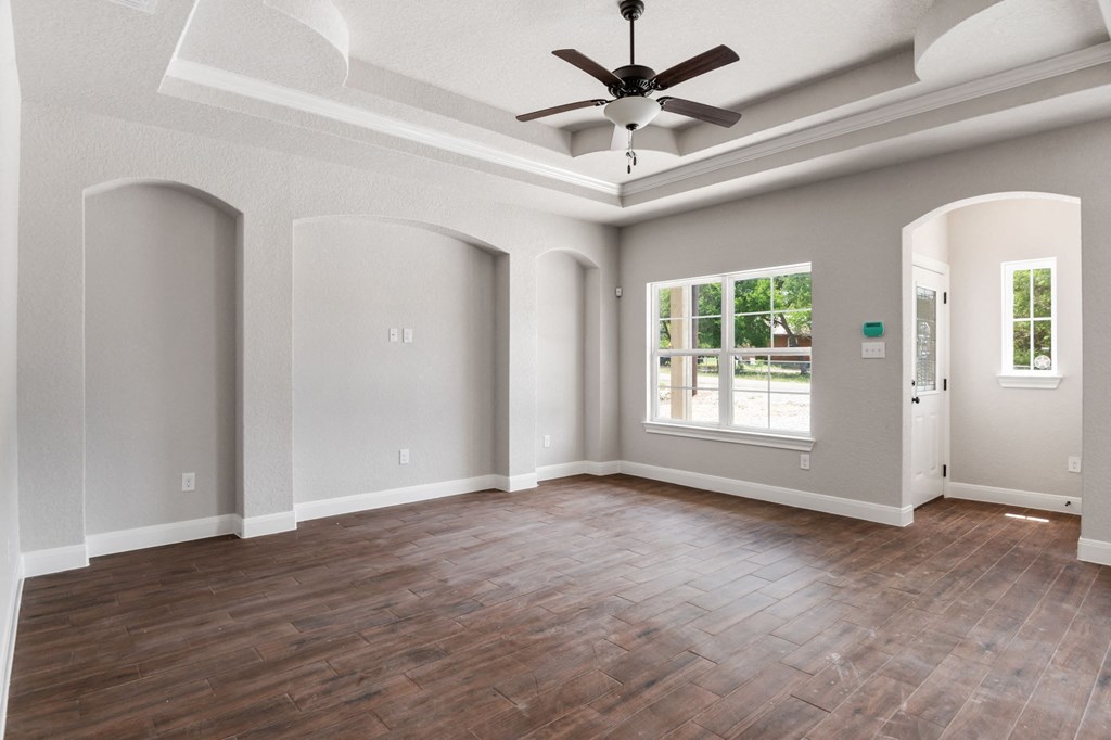 an empty living room with a ceiling fan and a window