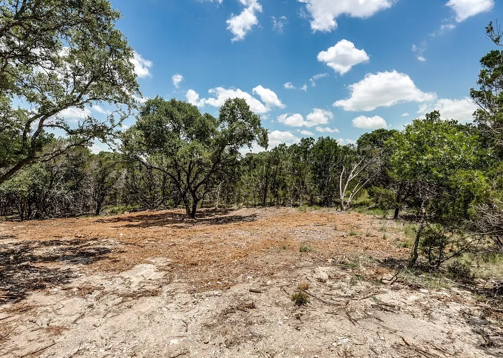 a dirt field with trees in the distance