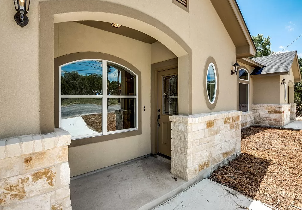 the front door of a house with stone pillars and a driveway