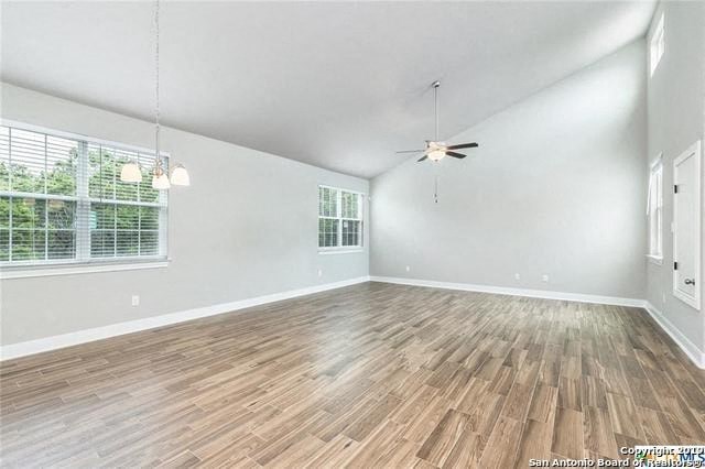 an empty living room with wood floors and a ceiling fan