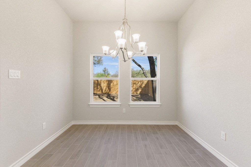 an empty living room with a window and a chandelier