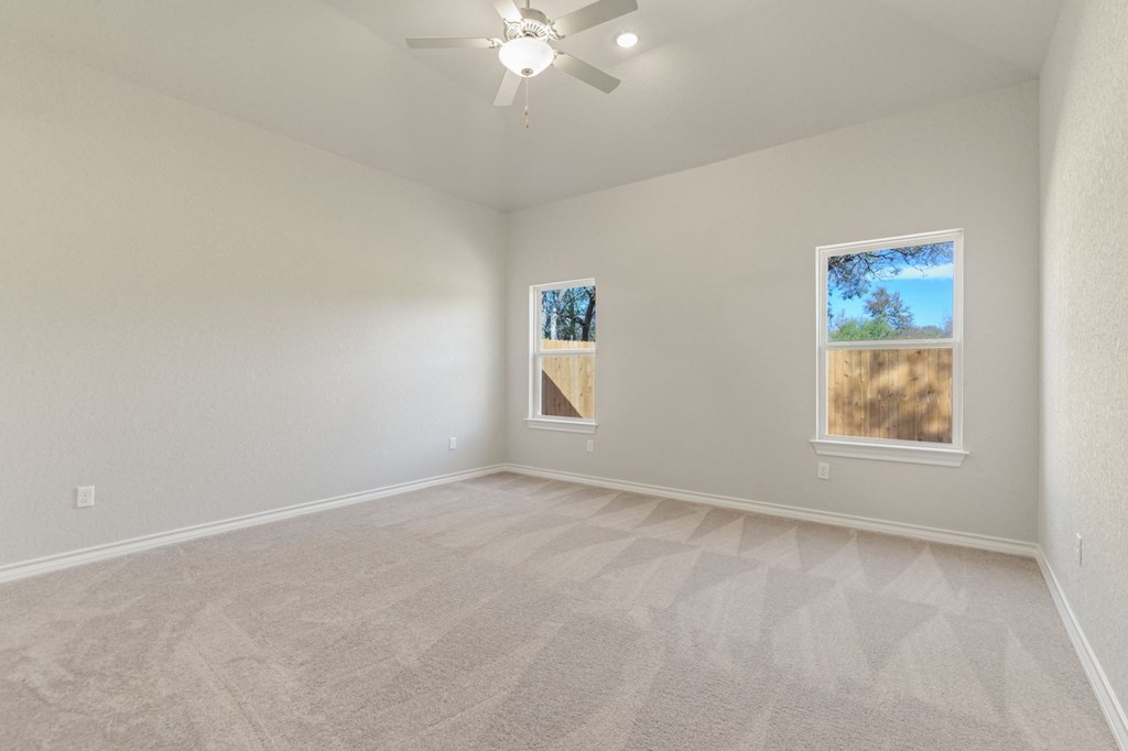 an empty living room with a ceiling fan and window