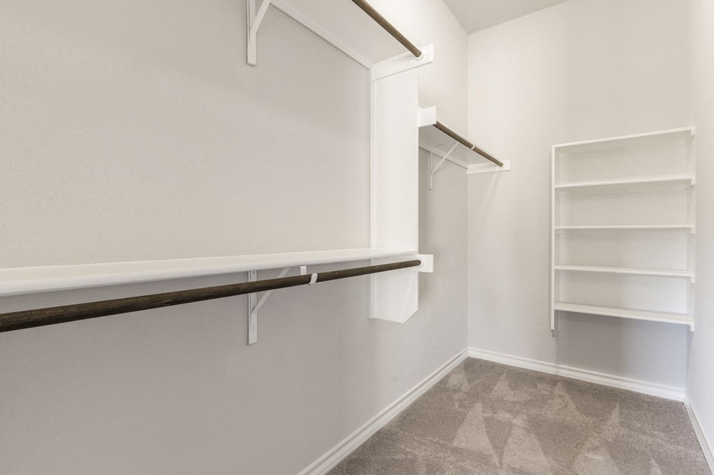 a walk in closet with white walls and shelves and empty shelves on the wall
