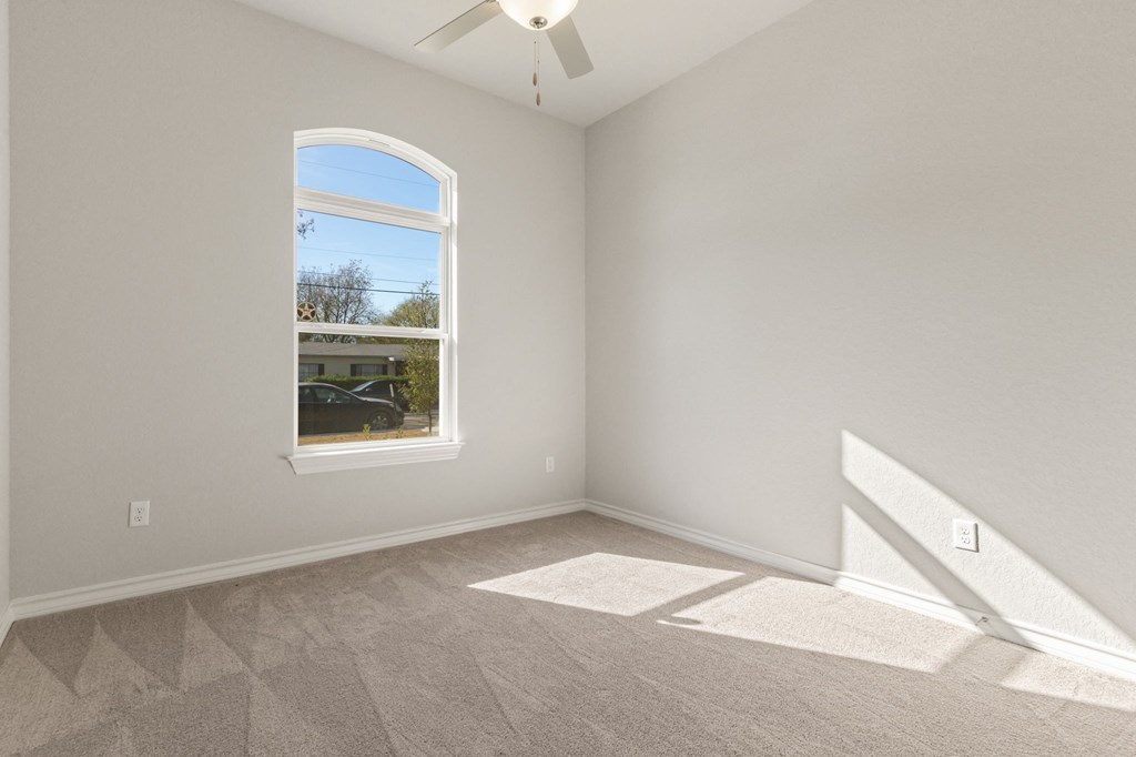 an empty room with a window and a ceiling fan