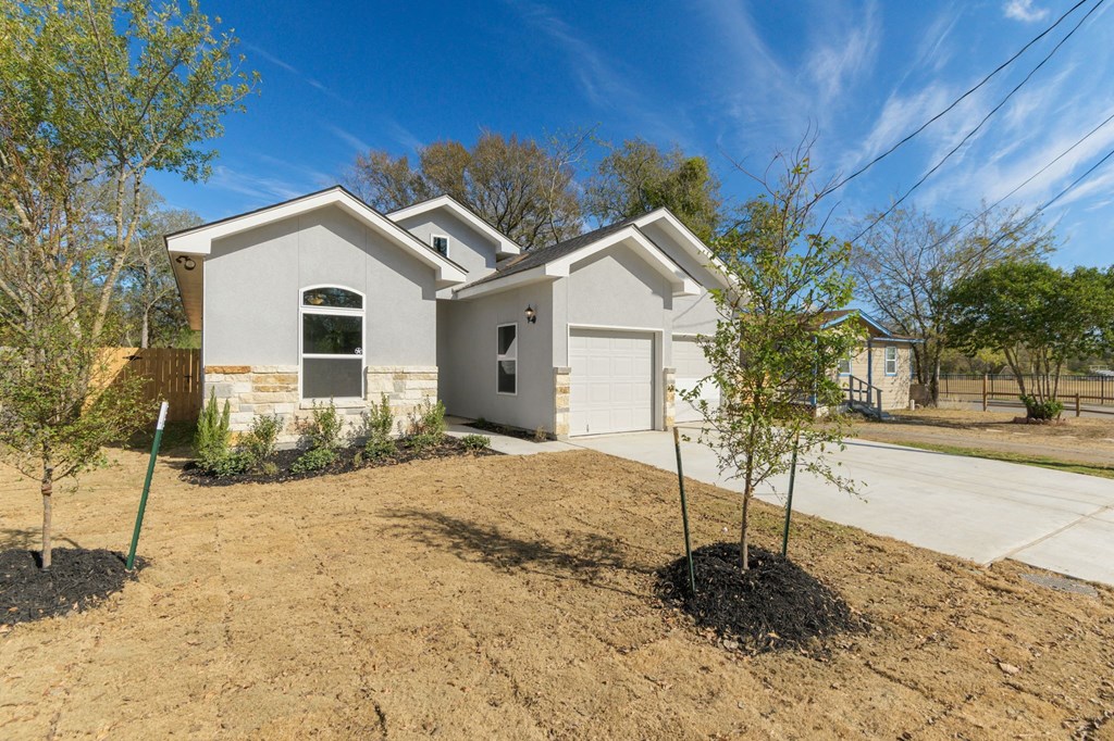 a white house with a garage and a dirt driveway