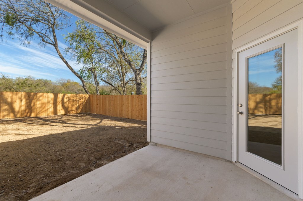 the covered porch of a white house with a door to the backyard