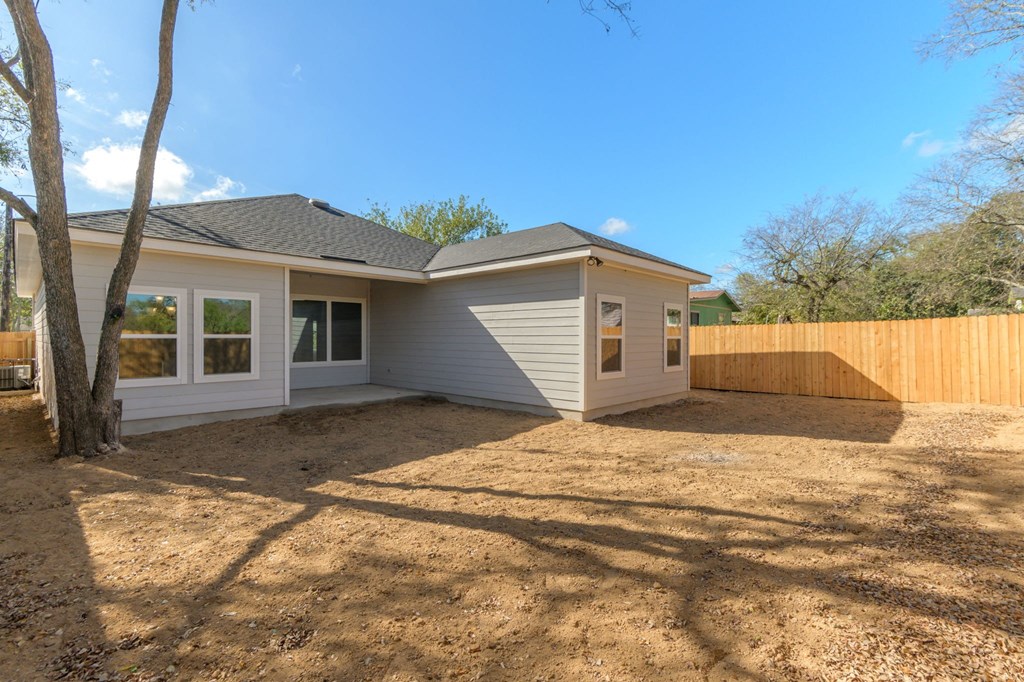 the backyard of a house with a gravel driveway and a fence