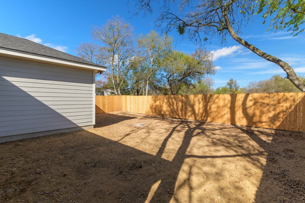 the side of a house with a fence and a tree