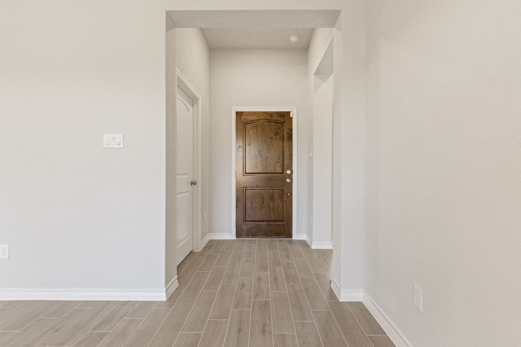 an empty hallway with a wooden door in a house