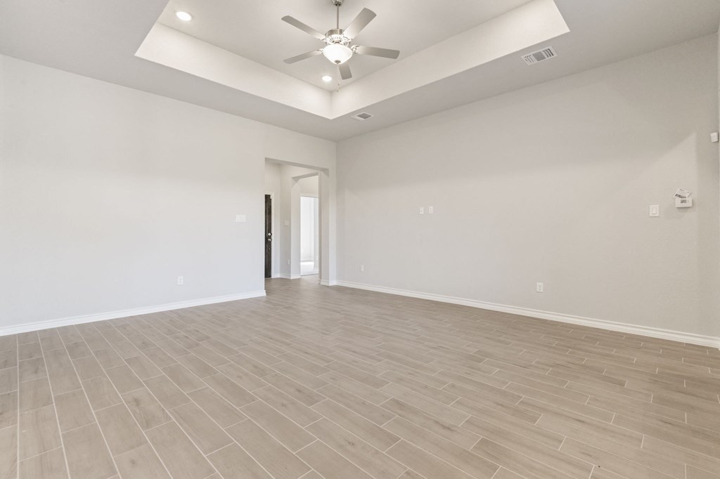 the living room of a new home with white walls and a ceiling fan