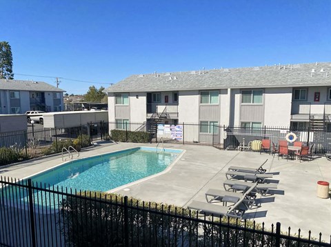 A pool surrounded by a black fence and chairs.