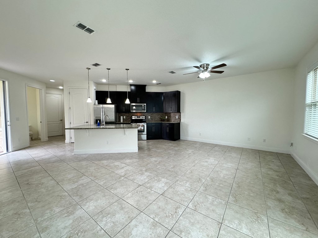 an empty kitchen and living room with a ceiling fan