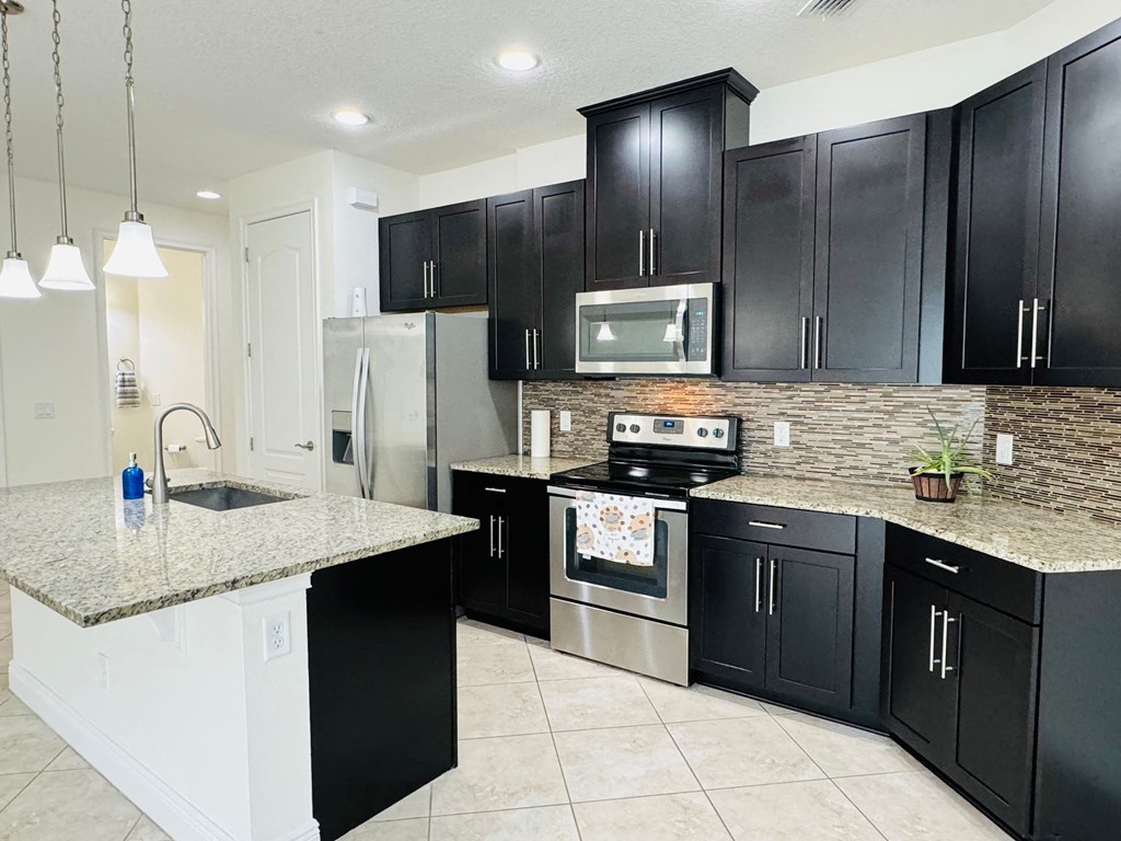 a large kitchen with black cabinets and granite counter tops