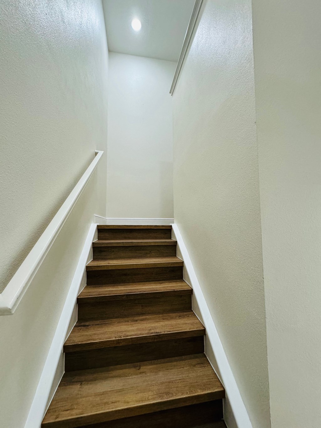stairs in a home with white walls and wood treads