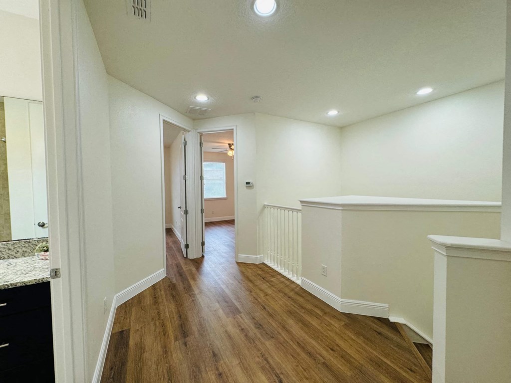 a renovated living room and hallway with white walls and wood floors