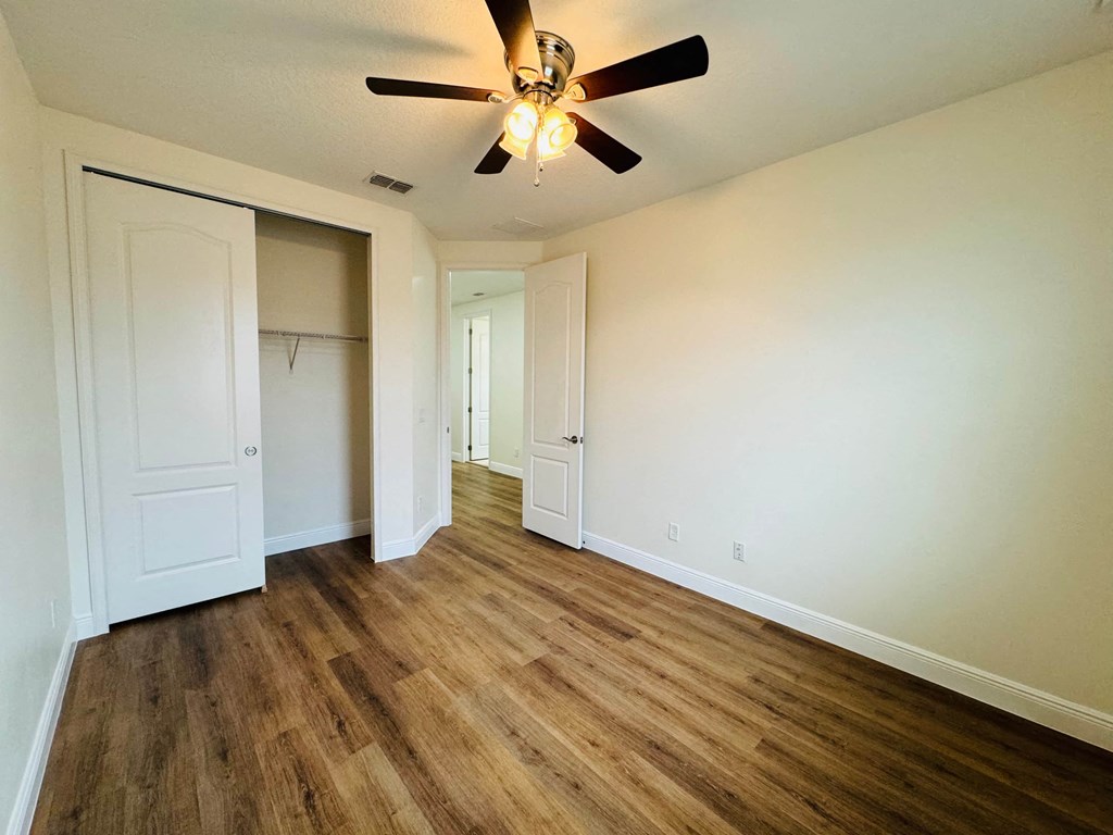 an empty living room with white walls and a ceiling fan