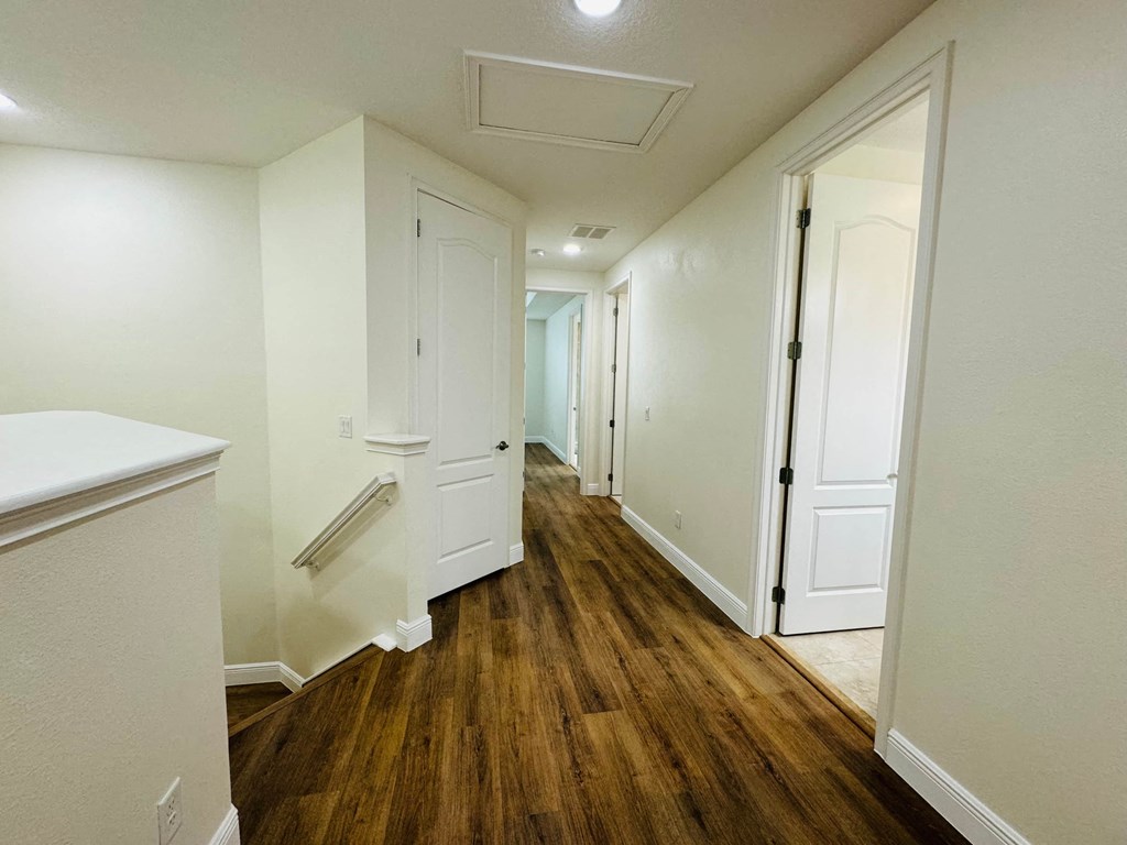 a renovated living room and hallway with wood floors and white walls