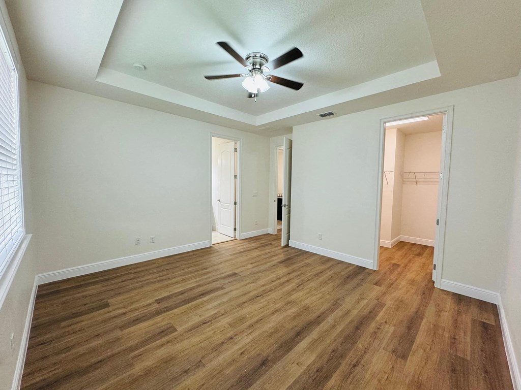 an empty living room with wood flooring and a ceiling fan
